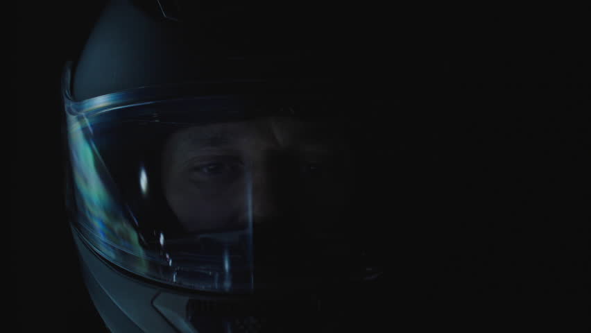 Man Riding at Night and Raising Helmet Visor to Rub Eyes from Fatigue in Low Light, Close-Up Front View, Driver Fatigue Concept.