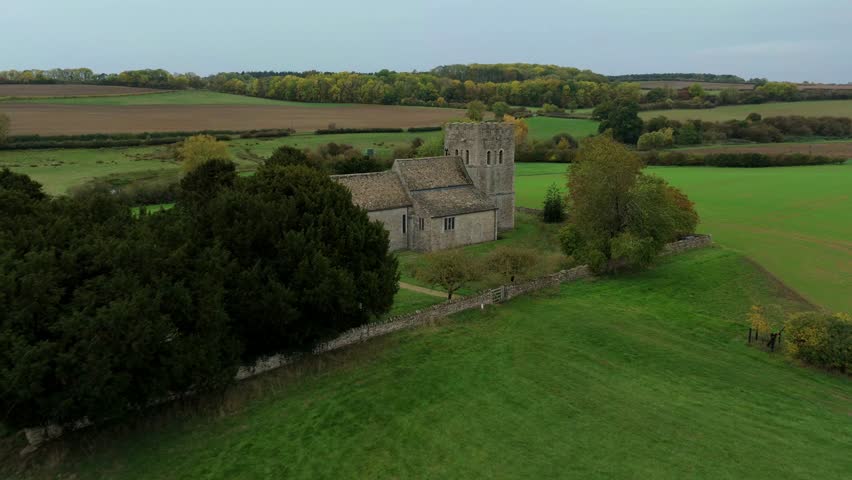 Aerial view of the church with its gray stone walls and tower, surrounded by lush green fields and trees, Stamford, England, United Kingdom.