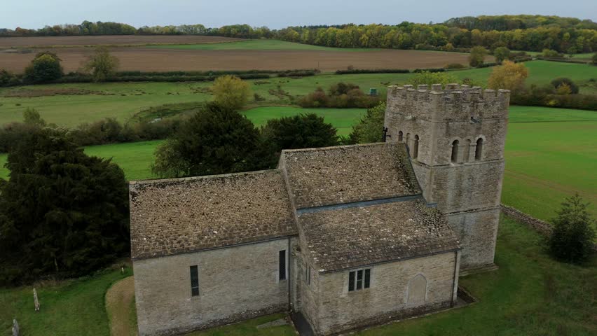 Aerial view of a stone church surrounded by green fields and trees, creating a serene and picturesque landscape, Stamford, England, United Kingdom.