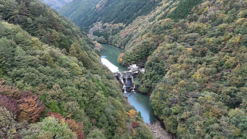 A beautiful mountain valley with a river running through it. The trees are lush and green, and the water is clear and calm. The scene is peaceful and serene, and it