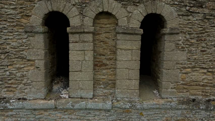 Aerial view of a stone church tower rising from lush green fields, a contrast against the muted tones of the sky, Stamford, England, United Kingdom.