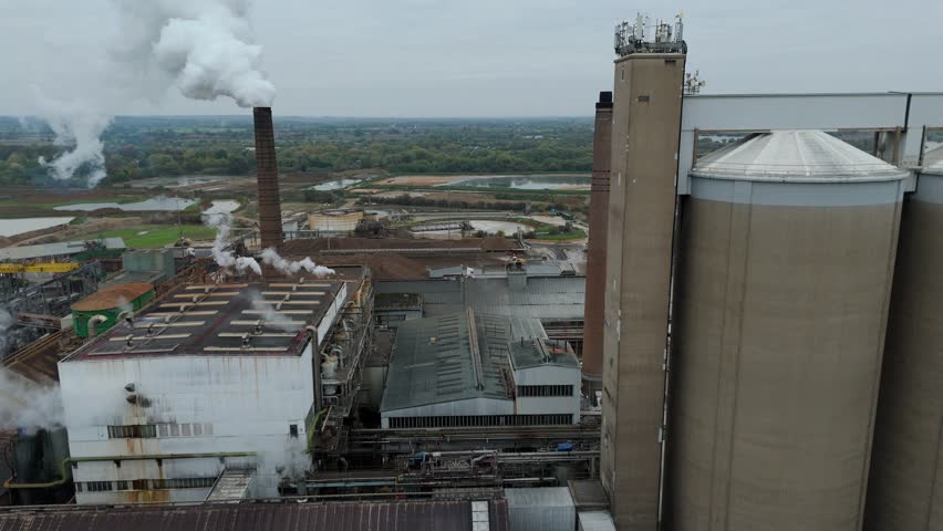 Aerial view of a sprawling industrial complex with chimneys releasing smoke, contrasting against the landscape, Newark, England, United Kingdom.