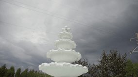 White decorative tiered fountain against a dramatic, cloudy sky with moody lighting and stormy weather vibes, creating a striking outdoor contrast. - Powered by Shutterstock - Get 15% off with code: PIKWIZARD15