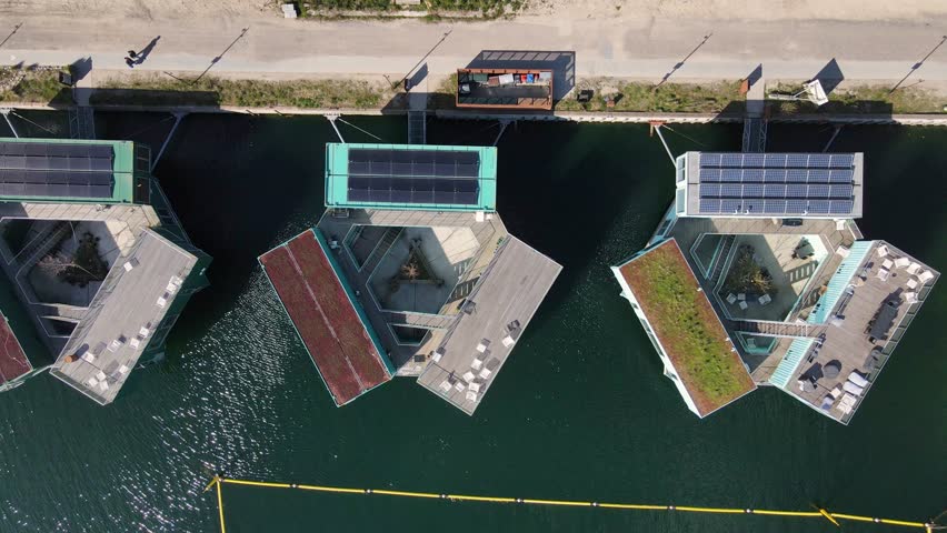 Aerial view of modern floating homes, adorned with solar panels and unique architectural designs, contrasting with the deep blue water, Copenhagen, Denmark.