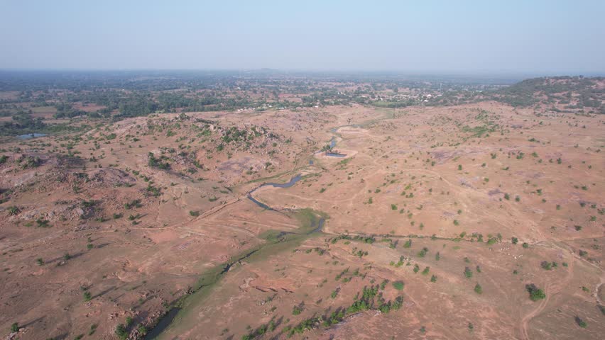Aerial drone view showcasing interconnected water conservation ponds and natural stream channels across a dry rocky landscape in Madhya Pradesh, India — sustainability and watershed management.