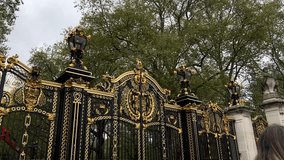 Cinematic zoom in on the ornate, gilded black iron gate of Buckingham Palace, London, UK. Close-up of the Royal Coat of Arms, golden accents, and a period lamp, British Monarchy, architecture, travel - Powered by Shutterstock - Get 15% off with code: PIKWIZARD15