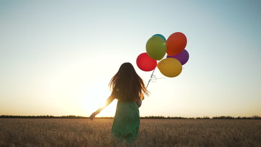 Woman with balloon enjoys fun under sky. Joyful woman green dress holds colorful balloon scenic field at sunset. Concept carefree happiness and freedom. Woman with balloon enjoys fun freedom outdoors.
