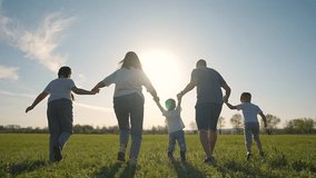 Backlit by sunset family walks on grass. Son joins walk near parents daughter. Scene glows sunlight. Grass reflects soft light at sunset. Son holds hands as group walks. Sunset grass son seen clearly. - Powered by Shutterstock - Get 15% off with code: PIKWIZARD15