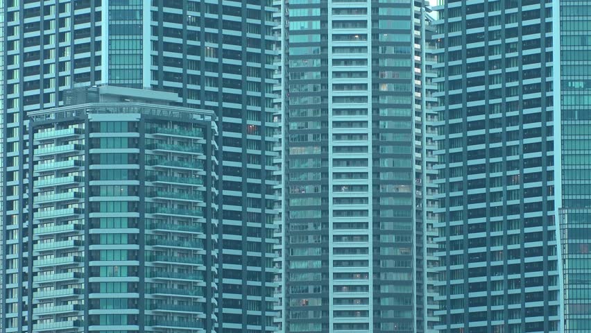 Time lapse shot of illuminated modern high rise residential apartment building with glowing windows in dense urban cityscape at night. Lifestyle and real estate concept. Shot in Tokyo, Japan.