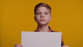 Boy Holding White Sheet of Paper for Unique Sign on Yellow Background - Powered by Shutterstock - Get 15% off with code: PIKWIZARD15