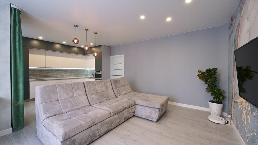 Modern living space featuring a plush sectional sofa, sleek kitchen in the background, and minimalist décor with warm lighting