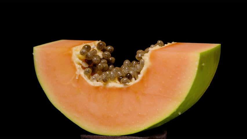 Seamless Loop Rotation of Papaya Wedge Showing Orange Flesh Green Skin and Black Seeds on Isolated Black Background, Captured in Profile, Concept of Fresh Exotic Fruit Display.