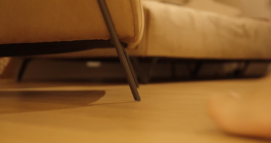 A man accidentally hits his bare foot against a metal chair leg while walking at home. Realistic everyday accident captured in warm lighting and slow motion.