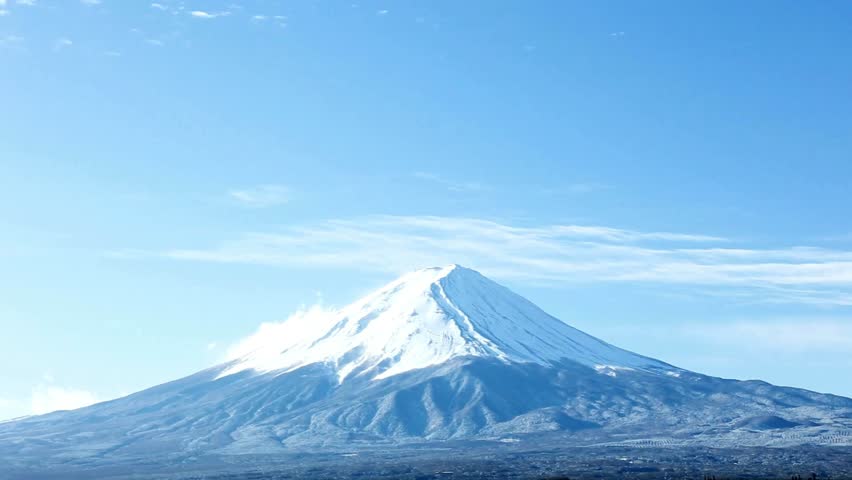 Majestic Mount Fuji rises against a vibrant blue sky. Snow covers its peak, highlighting summer greenery below. Perfect setting for nature lovers and tranquil moments.