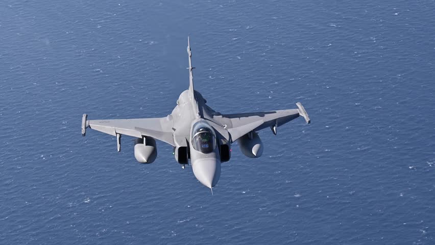 Saab JAS 39 Gripen fighter jet flying in the sky over sea