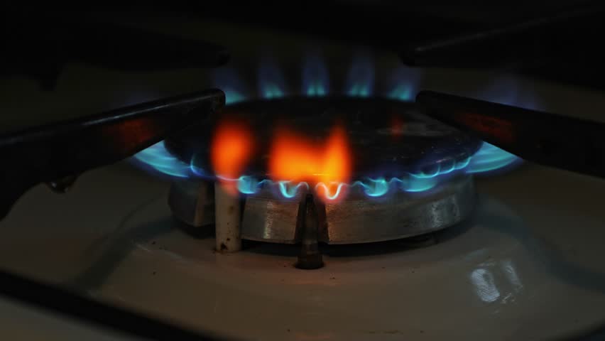 A gas burner with a blue flame of burning gas and red flashes, a concept of gas consumption and cost for households