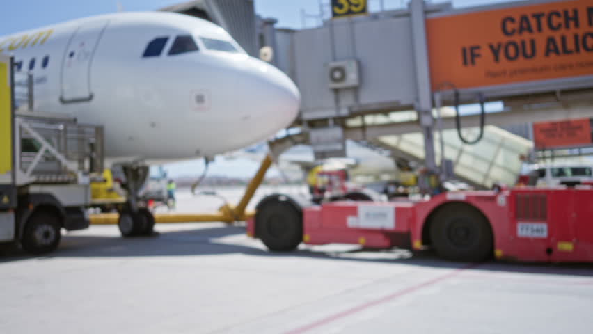Blurred airport apron with out of focus aircraft, ground vehicles and jet bridge bokeh station; background backplate copyspace template.