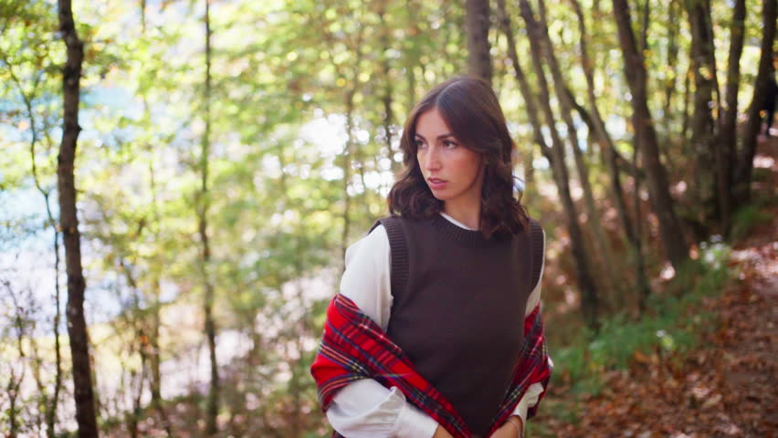 Woman walking in forest with red plaid blanket in autumn mood