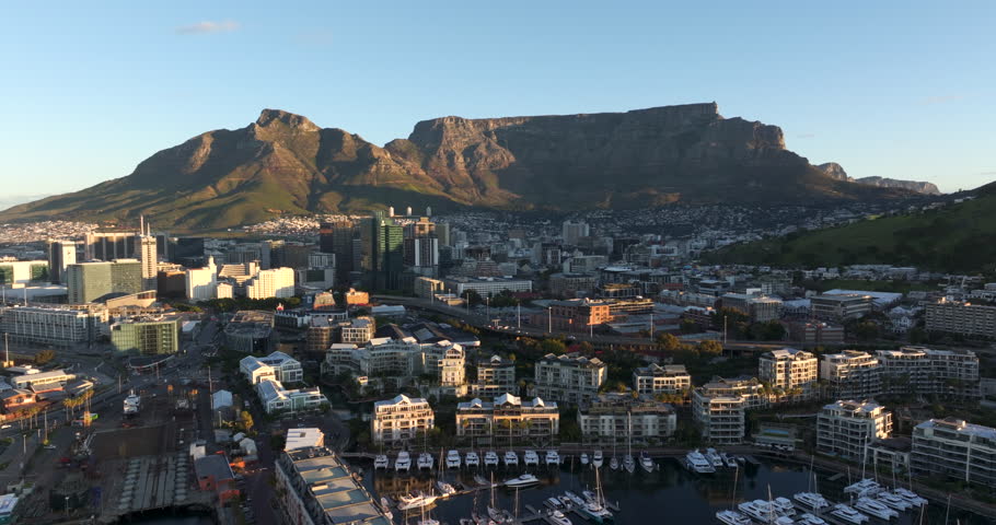 Aerial jib shot showing the Victoria and Alfred Waterfront and Table Mountain at sunset in Cape Town, South Africa.