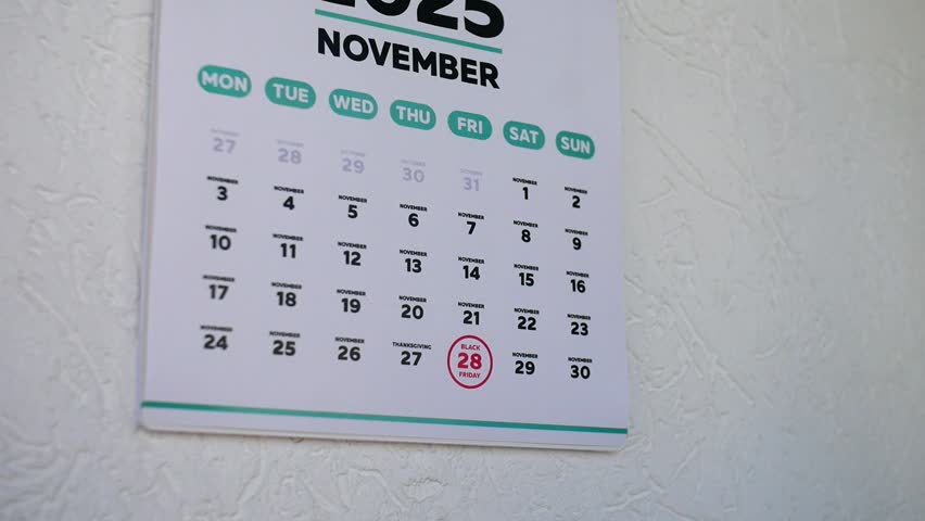 A man pointing finger to Black Friday date 2025 on a wall calendar