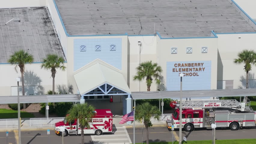 Ambulance and fire truck parked at main gate of public school as responders assist during health emergency.