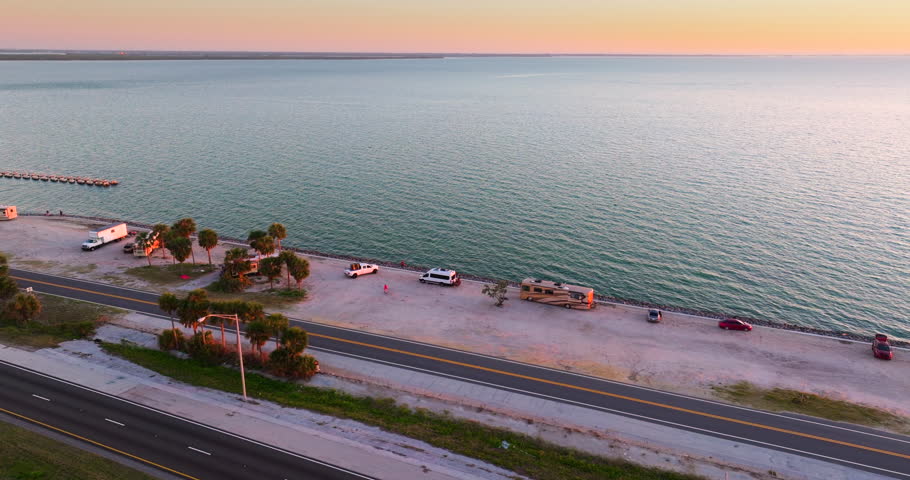 RV campers parked at sunset near Sunshine Skyway Bridge over Tampa Bay in Florida. Transportation infrastructure in America.