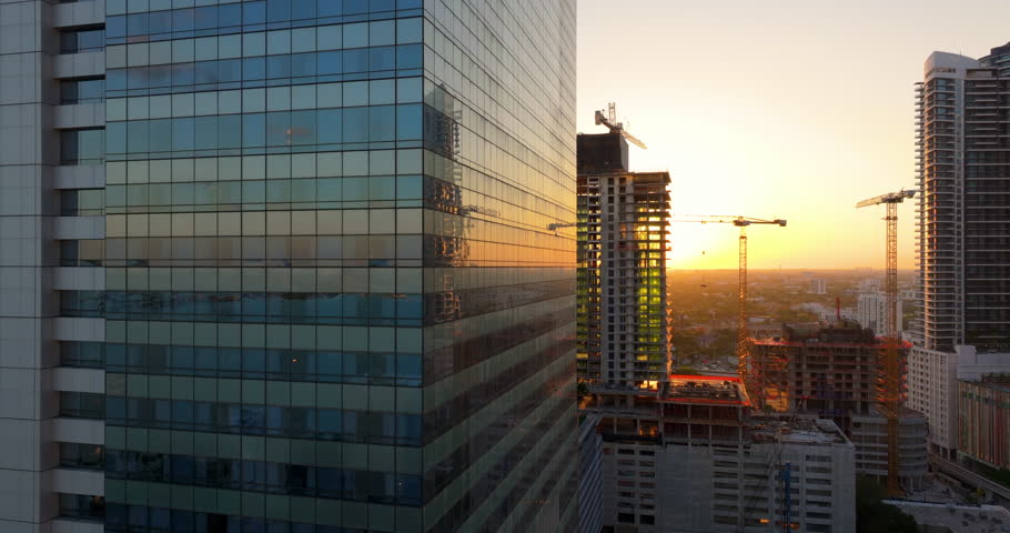 Tower cranes at high residential apartment building construction site at sunset. Real estate development in Miami urban area.