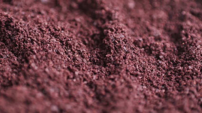 Close-up of a pile of acai powder isolated on a white background. The dark purple powder has a slightly grainy texture.