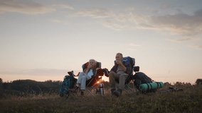 Camping chairs and backpacks rest as couple faces nature during back sunset. Senior couple drinks tea and relaxes feet enjoying quiet moment after long hike - Powered by Shutterstock - Get 15% off with code: PIKWIZARD15