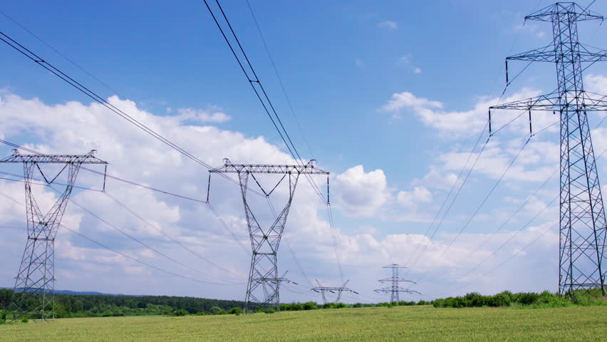 Power lines stretch across green fields under a bright blue sky