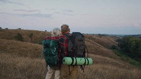 Hikers stand embracing on ridge slope watching evening valley. Grey-haired couple finishes Nordic walking and plans route for tomorrow enjoying silence together - Powered by Shutterstock - Get 15% off with code: PIKWIZARD15