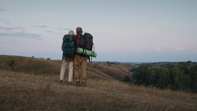 Man embraces wife standing arm in arm on hill slope top watching valley. Family couple breathes slowly and savors quiet pause after long hiking at sunset - Powered by Shutterstock - Get 15% off with code: PIKWIZARD15