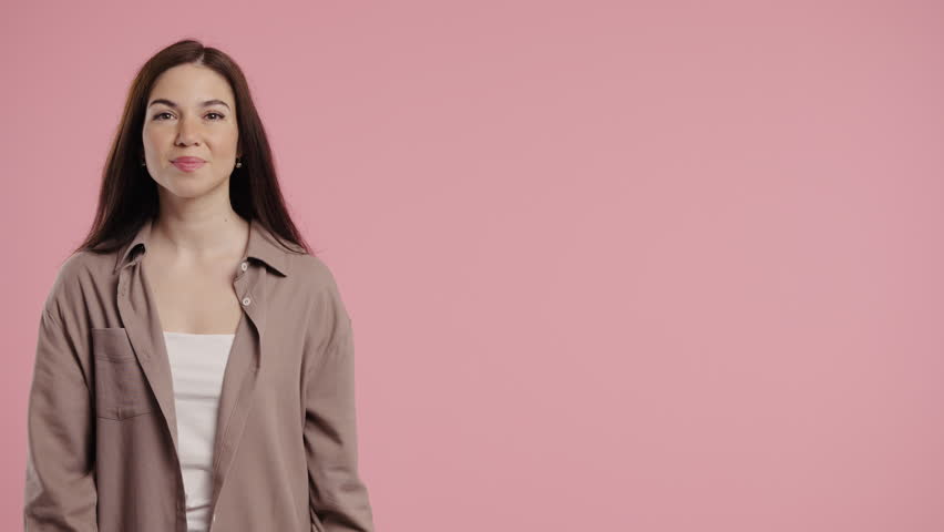Happy smiling woman presenting and showing something isolated on pink background. Portrait of pretty lady, pointing with arms on copy space.