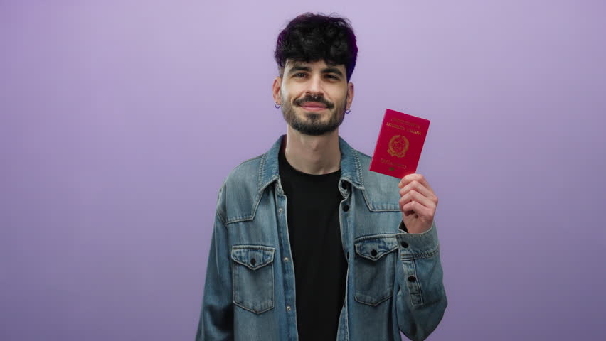 Man holding italian passport smiling against purple background wearing denim jacket and black t-shirt suggesting travel or identification theme