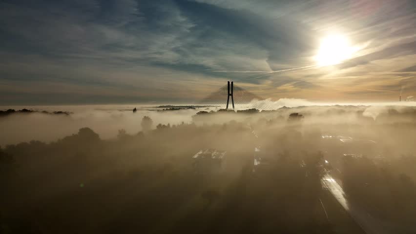 Aerial view of Redzin Bridge (Most Rędziński) in Wroclaw, Poland, surrounded by morning fog and forest under dramatic sunrise sky – scenic drone landscape of autumn mist and architecture