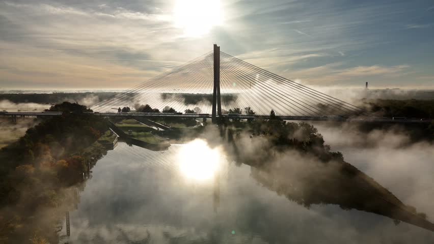 Aerial view of Redzin Bridge (Most Rędziński) in Wroclaw, Poland, surrounded by morning fog and forest under dramatic sunrise sky – scenic drone landscape of autumn mist and architecture
