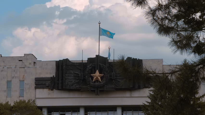 Kazakhstan flag is fluttering on the wind on top of a World War II Memorial in Panfilov Park, Almaty, Kazakhstan. Slow motion. High speed camera
