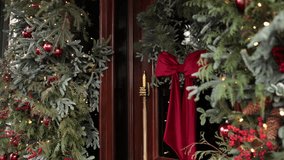 front door, Christmas vibes, seasonal home. Red velvet bow and shimmering ornaments add elegance to pine wreath hanging on festive front door. - Powered by Shutterstock - Get 15% off with code: PIKWIZARD15