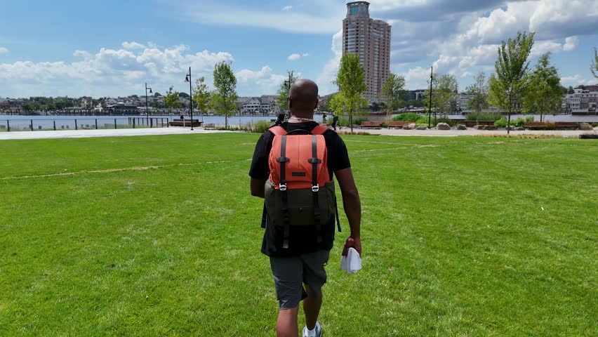 Footage of an African American man walking along the riverfront at Point Park in Baltimore Maryland USA