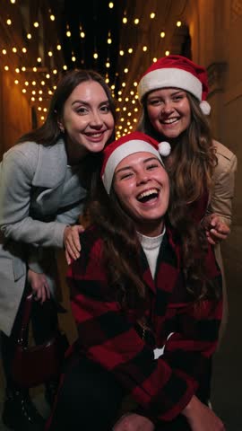 Three delighted friends sharing laughter and joy during the Christmas season while taking a cheerful holiday photo together, creating unforgettable memories filled with happiness and friendship.