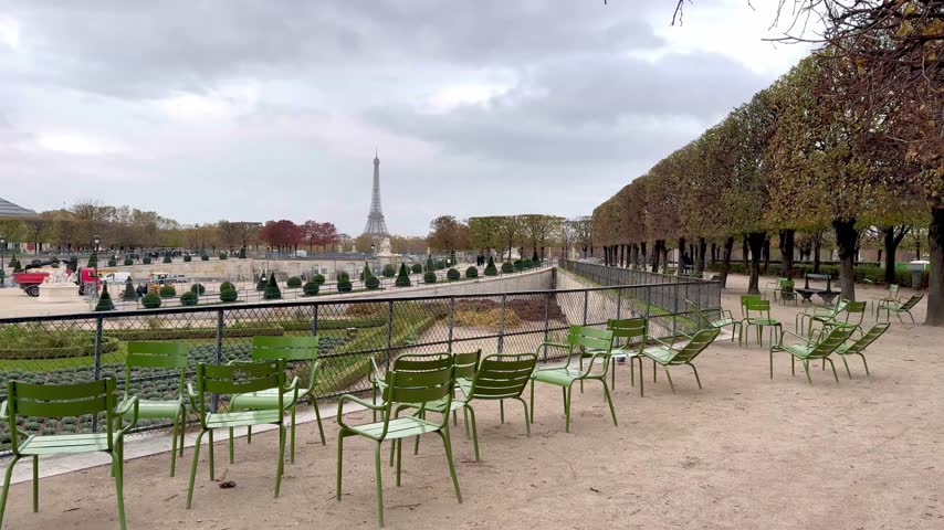 Peaceful Paris park scene with rows of classic green chairs in the Tuileries Garden and distant Eiffel Tower creating calm autumn atmosphere
