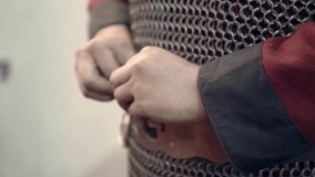 Scene of a medieval warrior donning his armor and accessories, preparing for battle. Dressing in his clothing, seen in his hands: belt, knives, chainmail. - Powered by Shutterstock - Get 15% off with code: PIKWIZARD15
