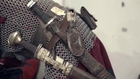Scene of a medieval warrior donning his armor and accessories, preparing for battle. Dressing in his clothing, seen in his hands: belt, knives, chainmail. - Powered by Shutterstock - Get 15% off with code: PIKWIZARD15