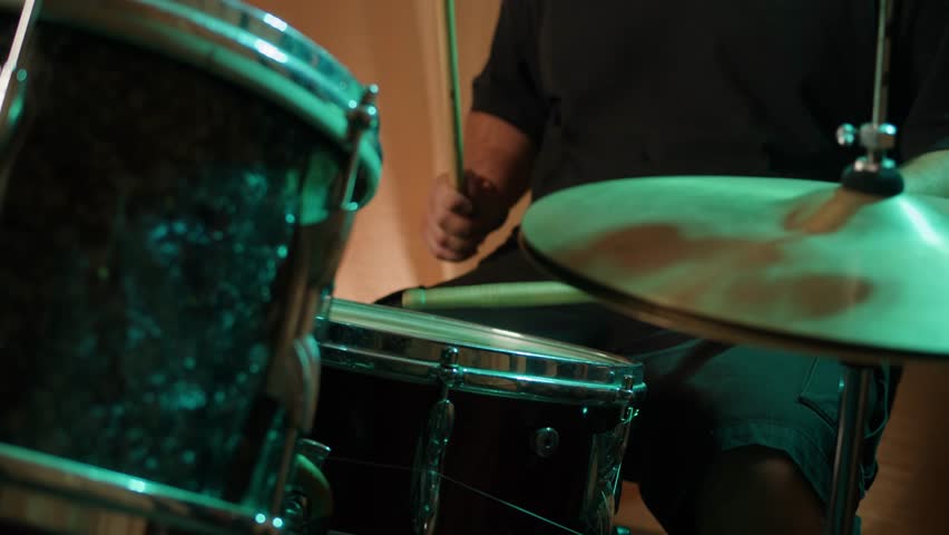 Drummer playing on concert, close up in studio, drummer hands hit the drum cymbal with drumstick in a dark studio. Drummer plays the drums in the recording studio. Music band rehearsal