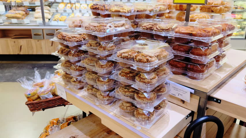 Variety of packed pastry in the grocery store with bakery products neatly displayed on shelves. Close up