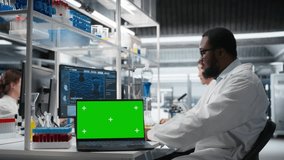 Cytotechnologist works on green screen laptop in lab, studying genomics information. African american man studies DNA strand mapping on mockup notebook, contributing to scientific innovation, camera A - Powered by Shutterstock - Get 15% off with code: PIKWIZARD15