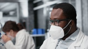 Lab scientist removing protective face mask to scratch beard while using PC. Expert wearing medical mask in contagious workspace studies DNA strand mapping with genomics analysis program, camera B - Powered by Shutterstock - Get 15% off with code: PIKWIZARD15