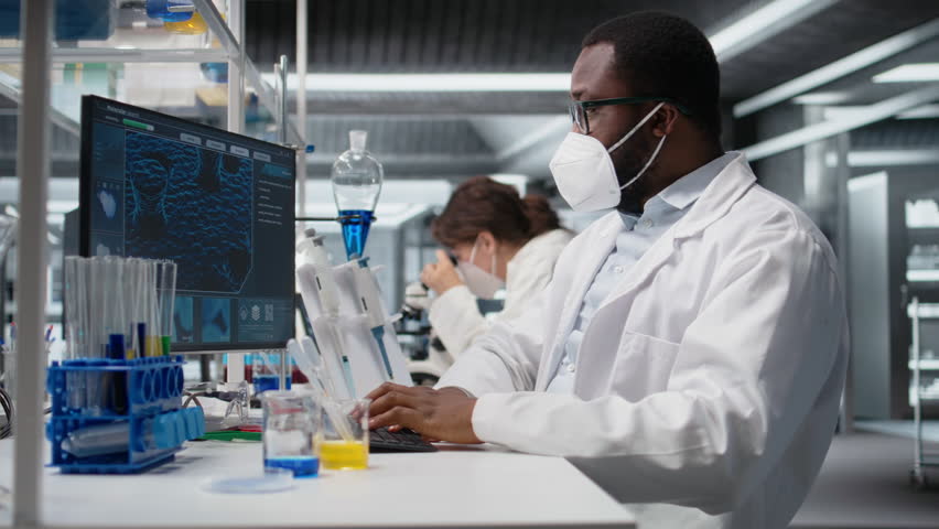 Lab scientist removing protective face mask to scratch beard while using PC. Expert wearing medical mask in contagious workspace studies DNA strand mapping with genomics analysis program, camera A - Powered by Shutterstock - Get 15% off with code: PIKWIZARD15