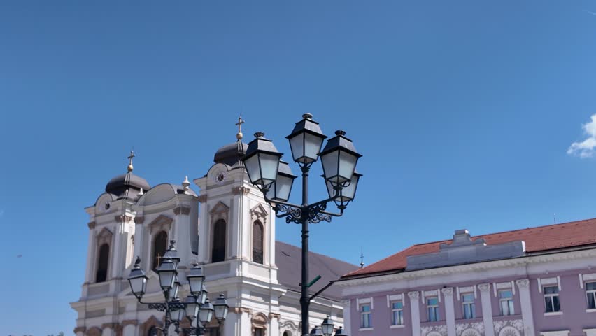 Scenic view of Saint George’s Catholic Cathedral in Timisoara, Romania, with elegant lamp posts in the foreground adding depth and charm to the historic architecture.