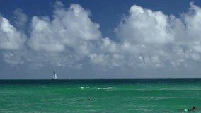 Turquoise water with a small wave breaks on Waikiki Beach, Honolulu, with a sailboat visible on the horizon. Bright cumulus clouds fill the blue sky. A perfect tropical paradise background. - Powered by Shutterstock - Get 15% off with code: PIKWIZARD15